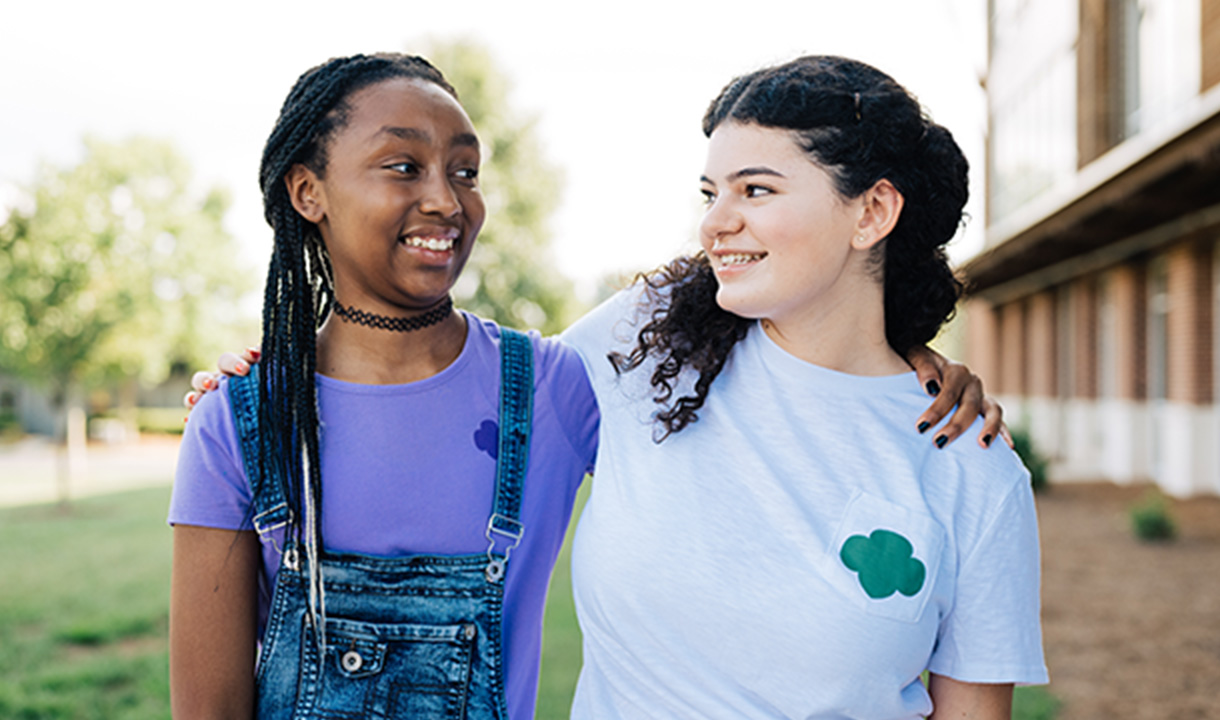Two girls with their arms around each other's shoulders