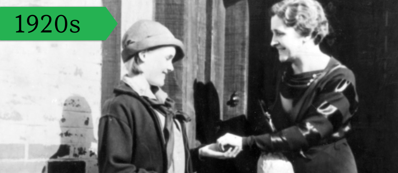 A Girl Scout sells cookies door-to-door, 1928. 
