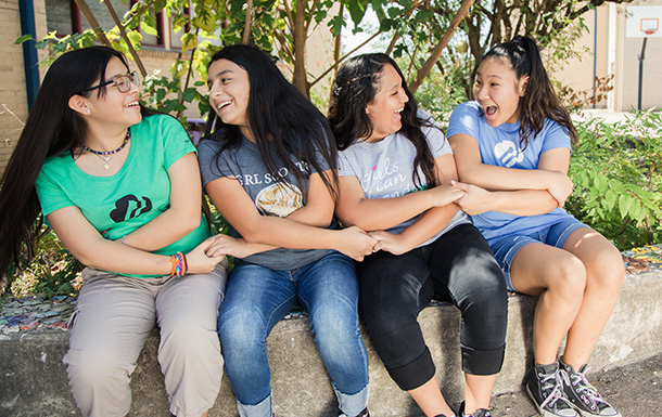 Four Girl Scouts engaged in a group friendship handshake 
