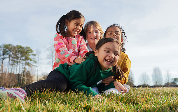 Tres Daisy Girl Scouts haciéndole cosquillas a su amiga