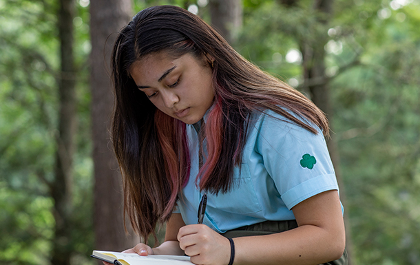 Older Girl Scout journaling outside